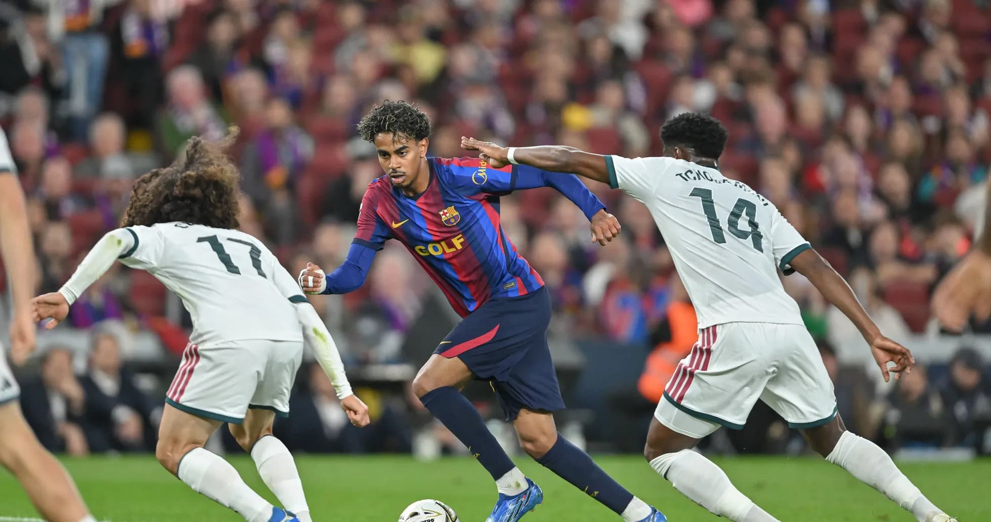 Barcelona player dribbling past two defenders during match