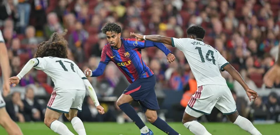 Barcelona player dribbling past two defenders during match