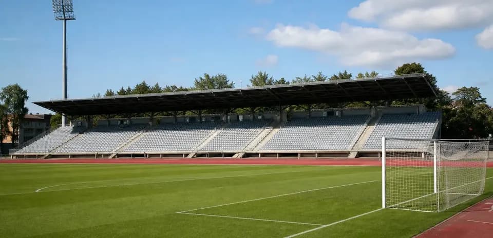 Empty football stadium with green pitch and bleachers