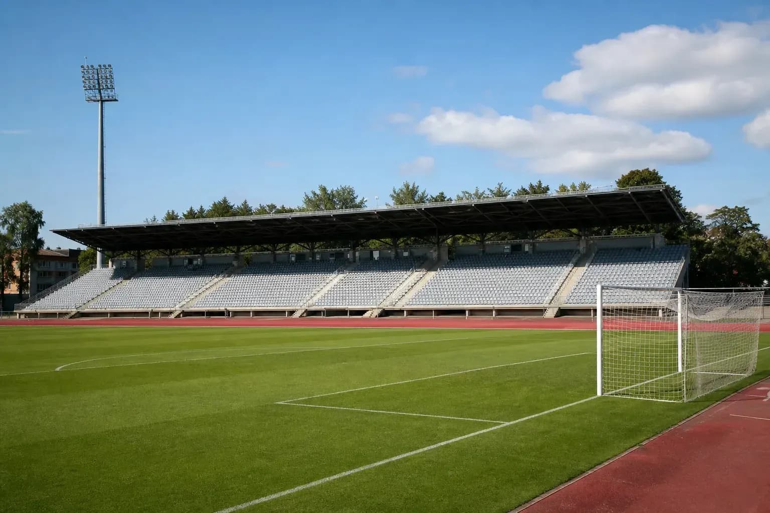 Empty football stadium with green pitch and bleachers