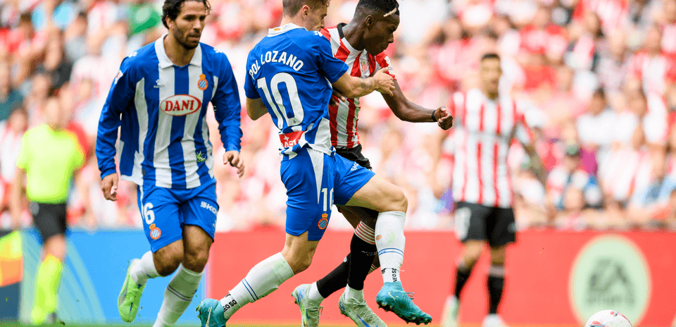 Espanyol player challenging Athletic Club opponent