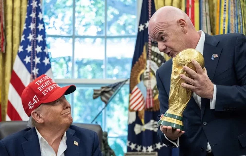 Man holding FIFA World Cup trophy with another man