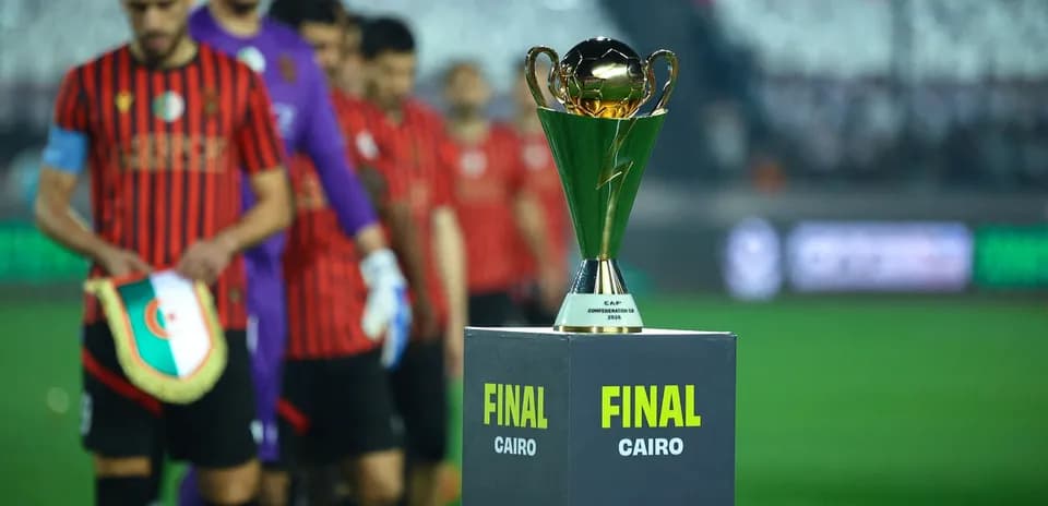 Players walking past the CAF Confederation Cup trophy