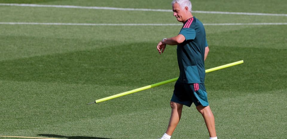 Coach walking on pitch with training equipment