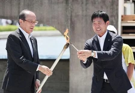 Two officials lighting a ceremonial torch together
