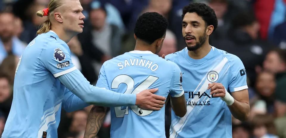 Three Manchester City players celebrating on the pitch
