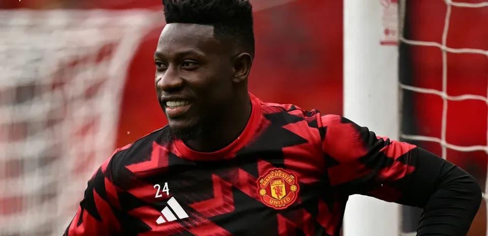 Goalkeeper in Manchester United kit smiling on pitch
