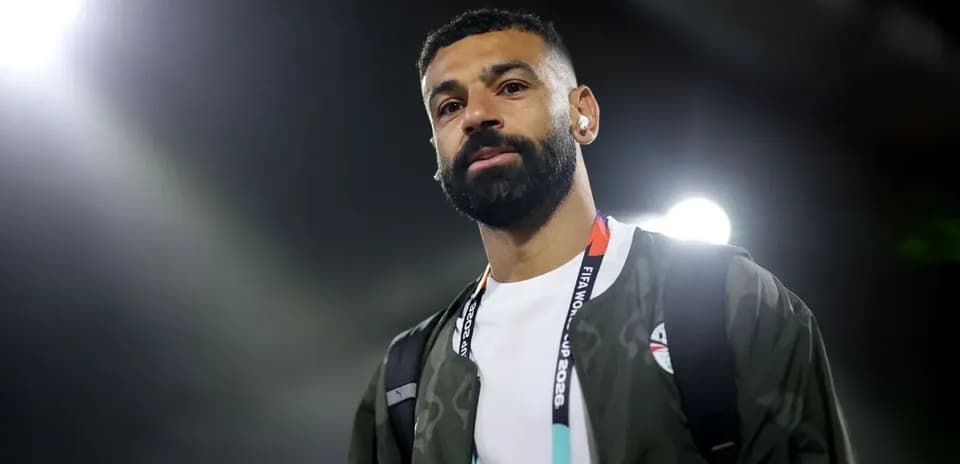 Player walking with headphones and backpack in stadium