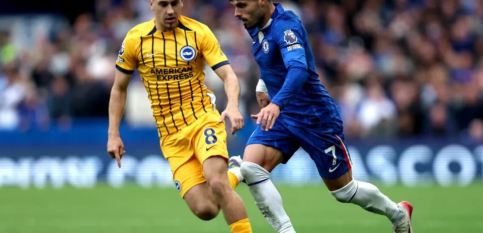 Brighton player challenging Chelsea player for the ball