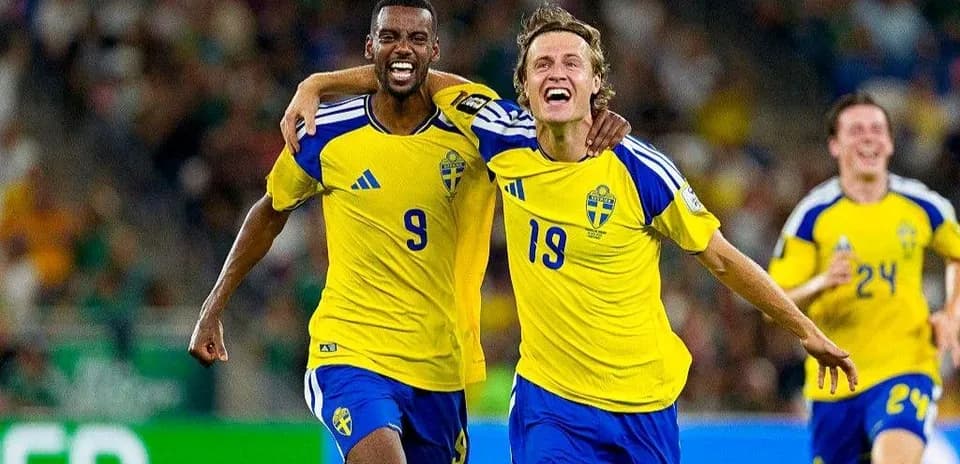 Two Swedish players celebrating a goal on field