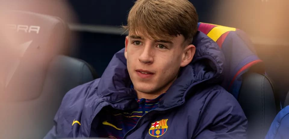 Young player seated on bench wearing Barcelona jacket