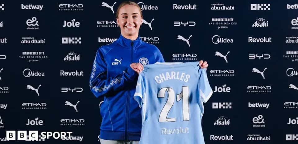 Player holding Manchester City jersey at press event
