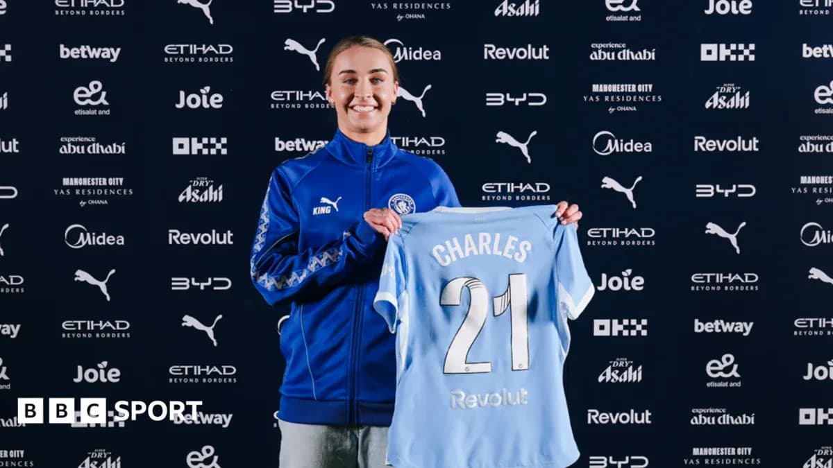 Player holding Manchester City jersey at press event