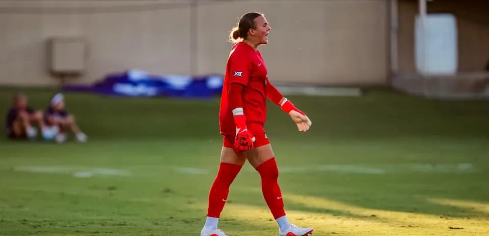 Goalkeeper in red uniform walking on field