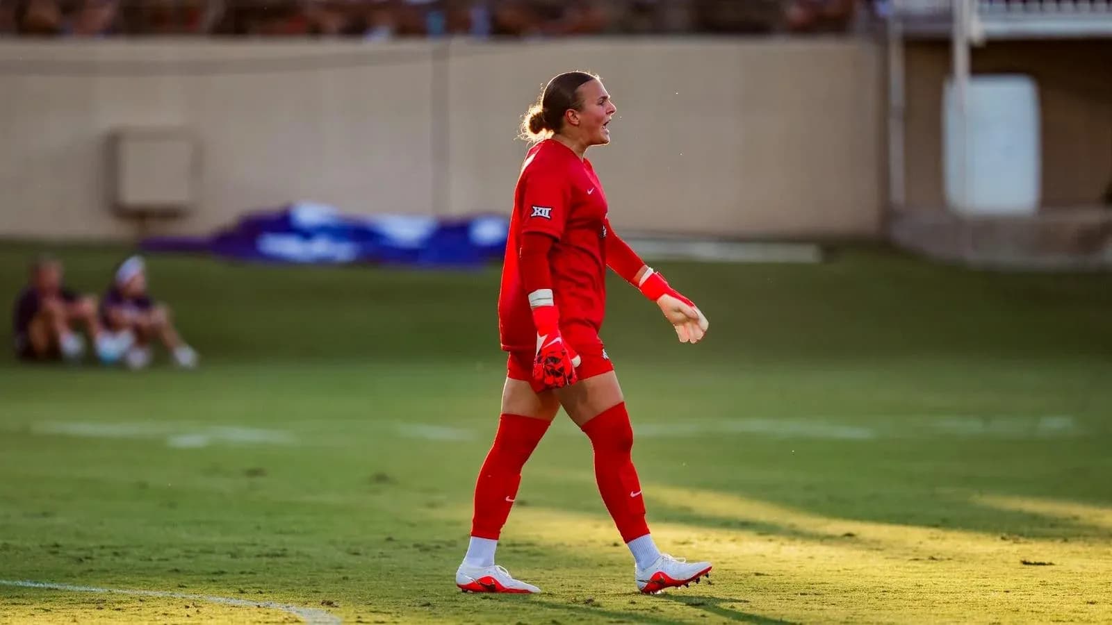 Goalkeeper in red uniform walking on field