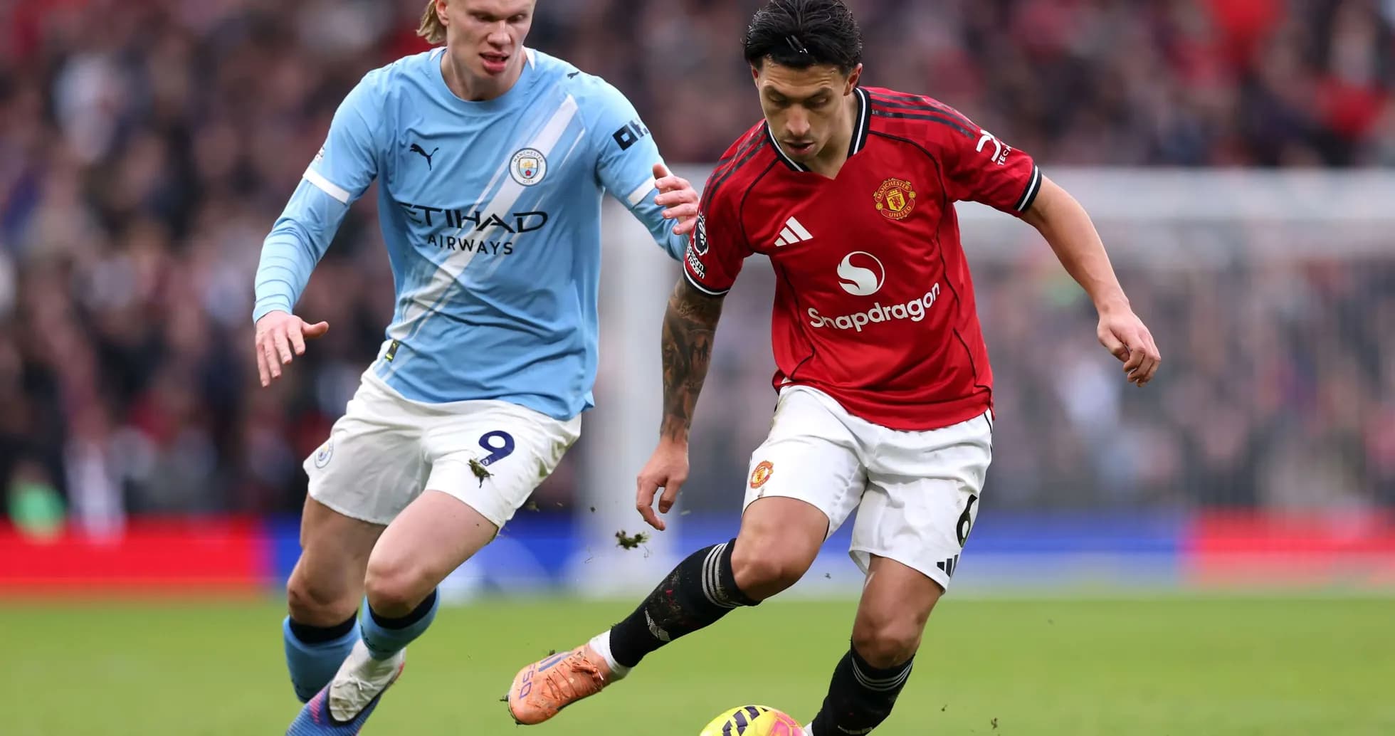 Manchester United player dribbling past Manchester City opponent