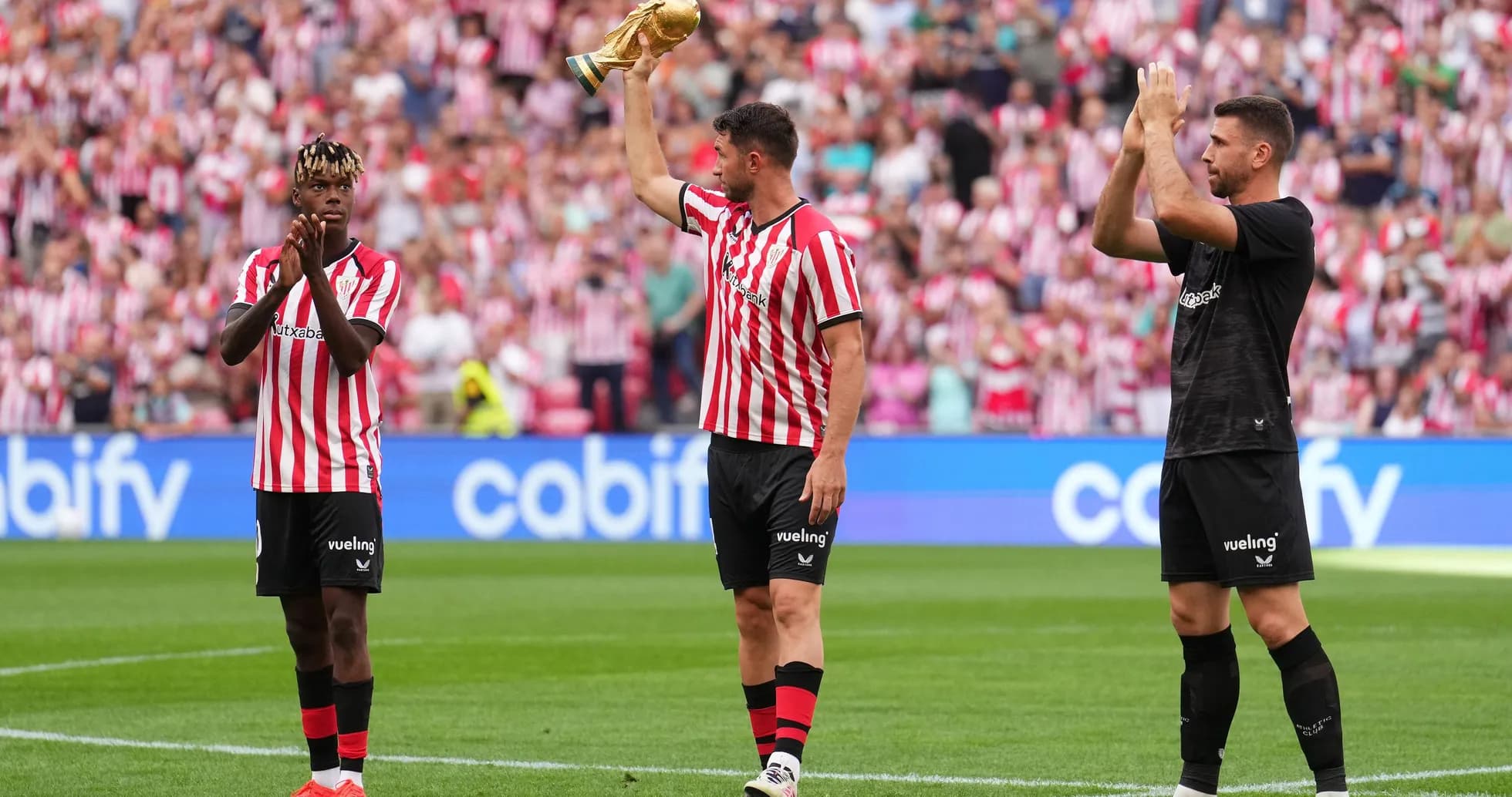 Athletic Club players celebrating with trophy on field