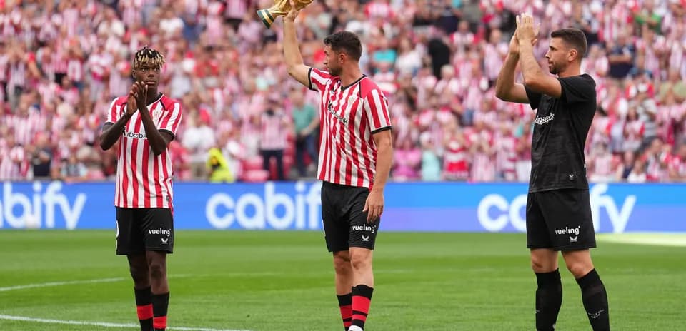 Athletic Club players celebrating with trophy on field