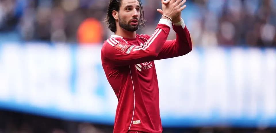 Player in red jersey applauding fans during match