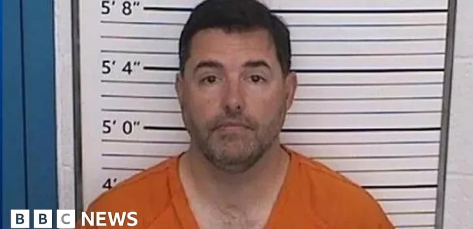 Man in orange jumpsuit standing against height chart