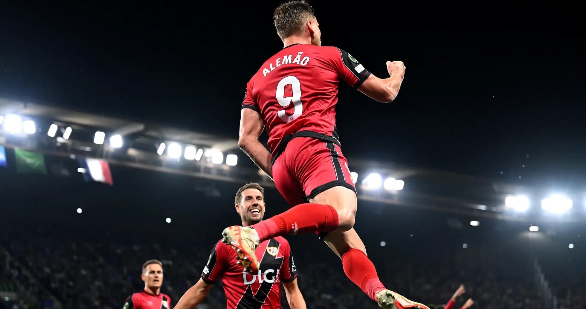 Player celebrating goal with teammates in stadium