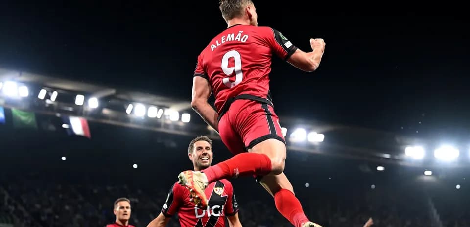 Player celebrating goal with teammates in stadium