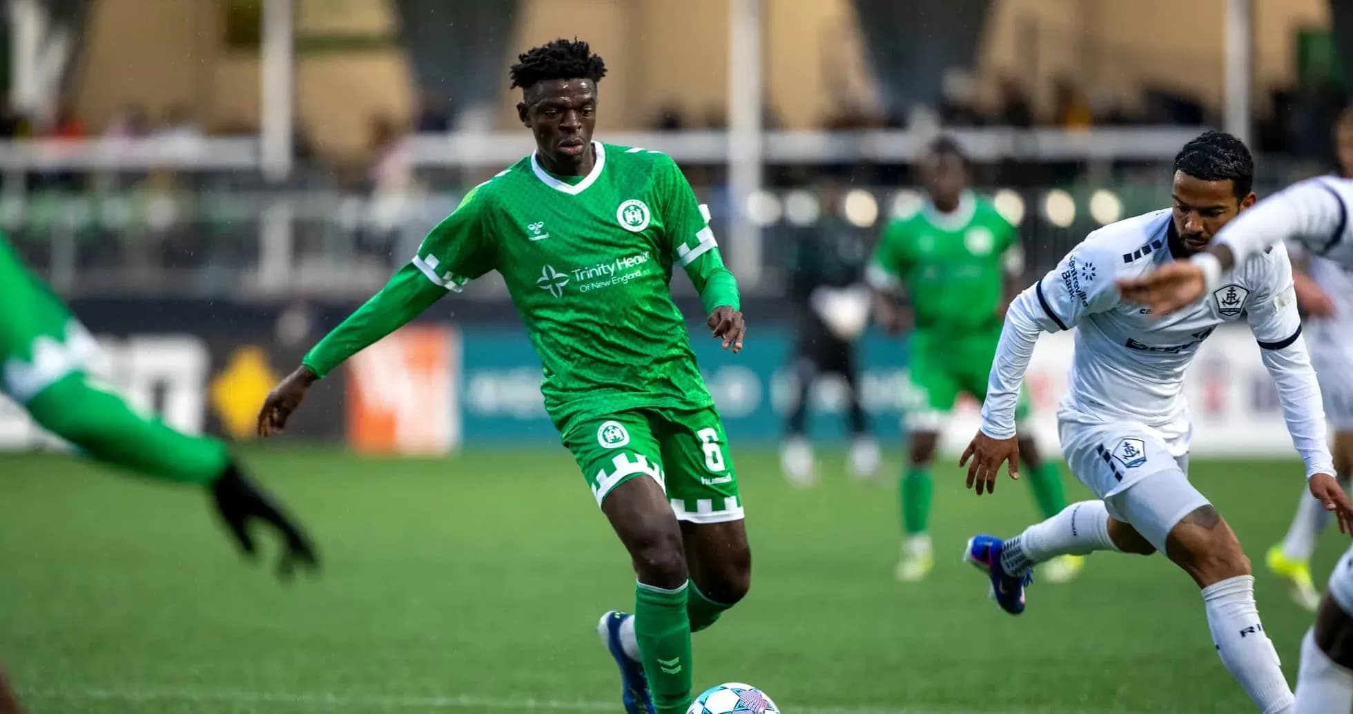 Player in green jersey dribbling ball during match