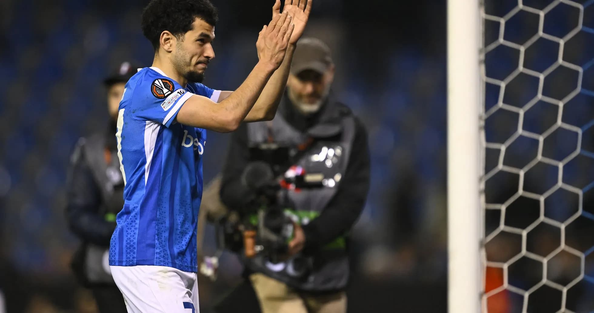 Player applauding fans near goal post after match