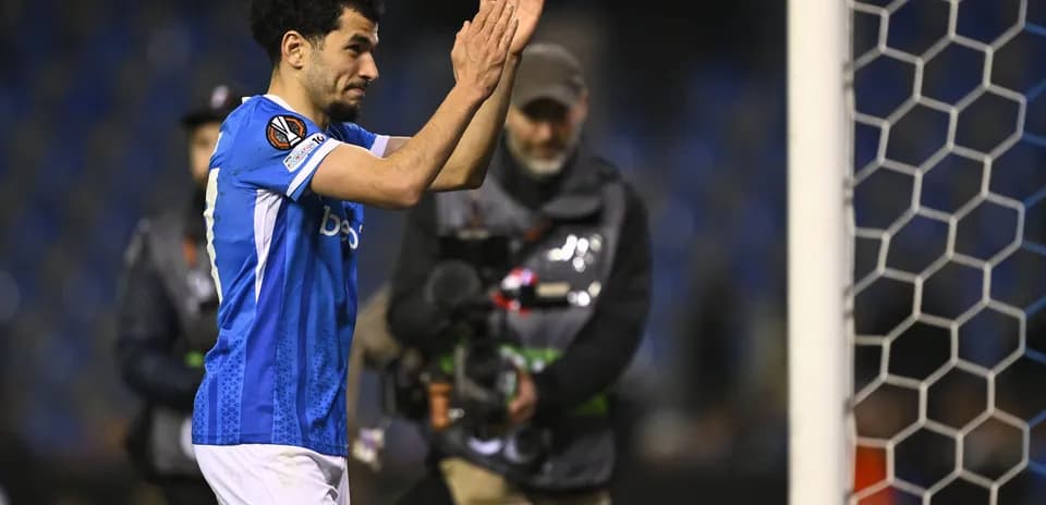 Player applauding fans near goal post after match