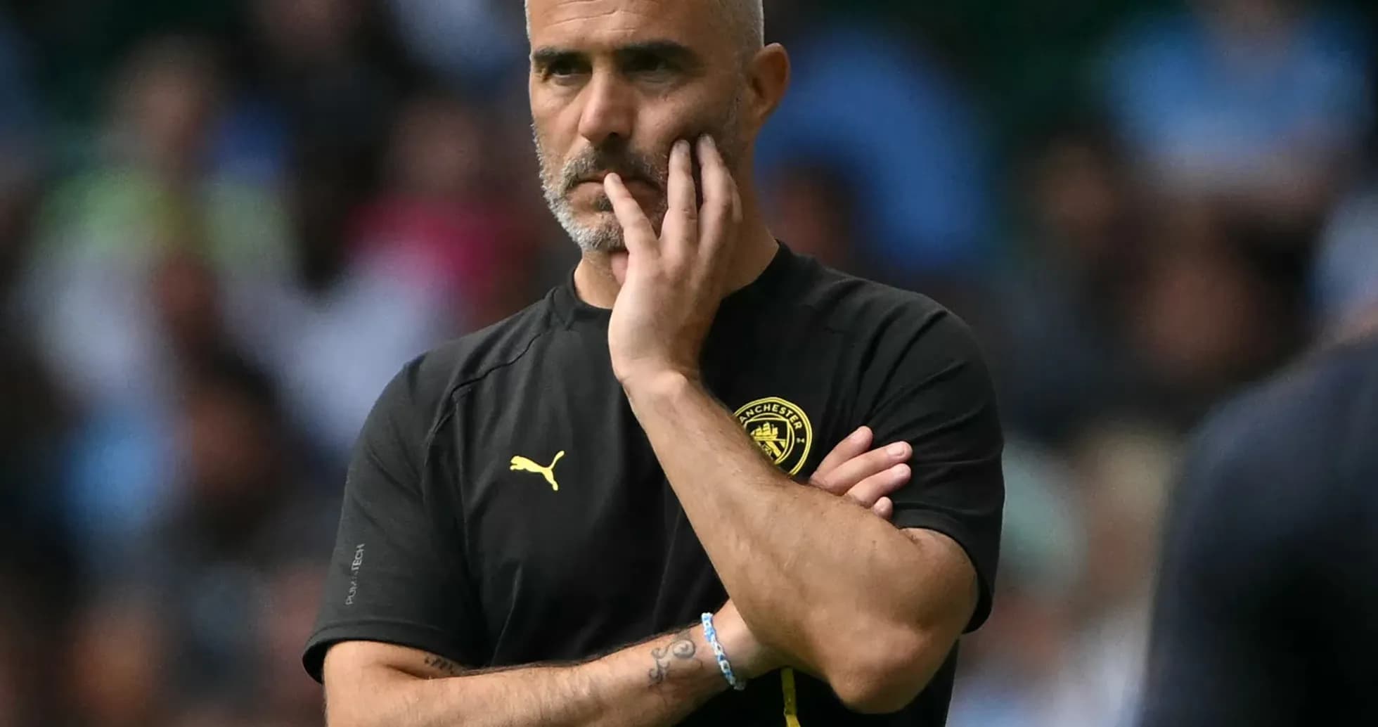 Coach observing the match with a thoughtful expression