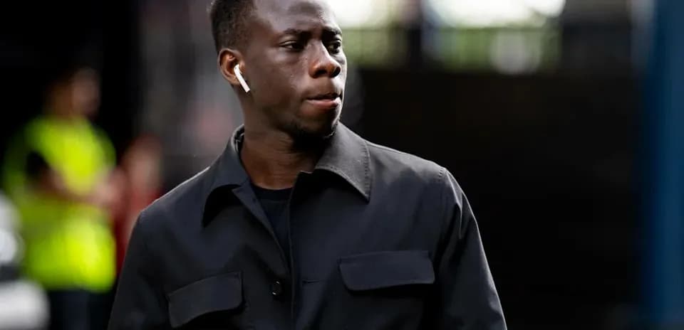 Player walking with AirPods in a black jacket