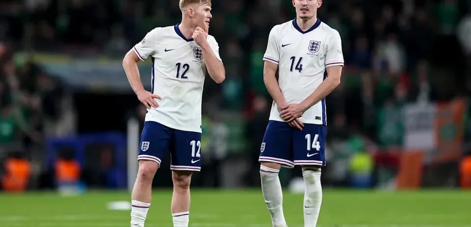 Two England players standing on the pitch post-match