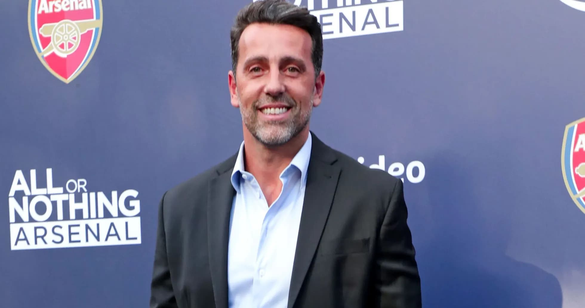 Man in suit smiling at promotional event backdrop