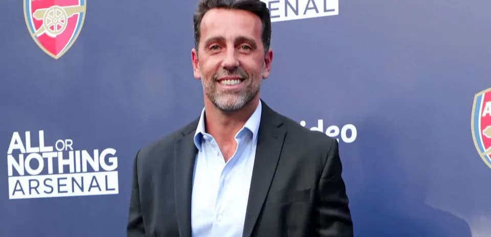 Man in suit smiling at promotional event backdrop