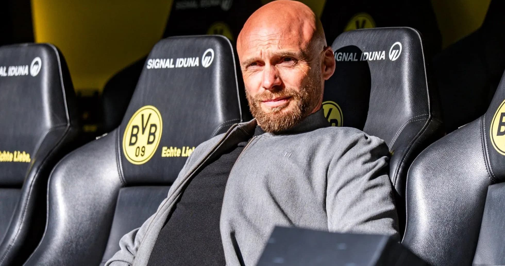 Coach seated on bench at stadium during match