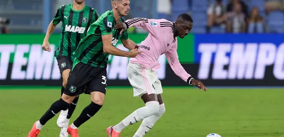 Sassuolo player challenges Juventus opponent for the ball