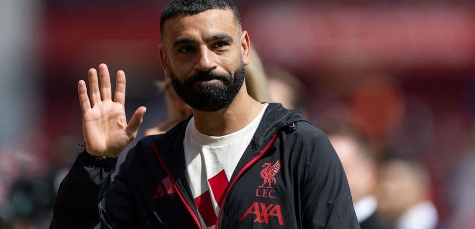Player waving while wearing Liverpool FC jacket