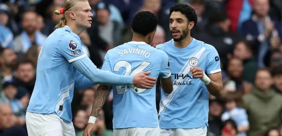 Three Manchester City players discussing on the field