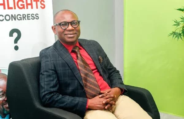 Man in suit sitting on chair, smiling
