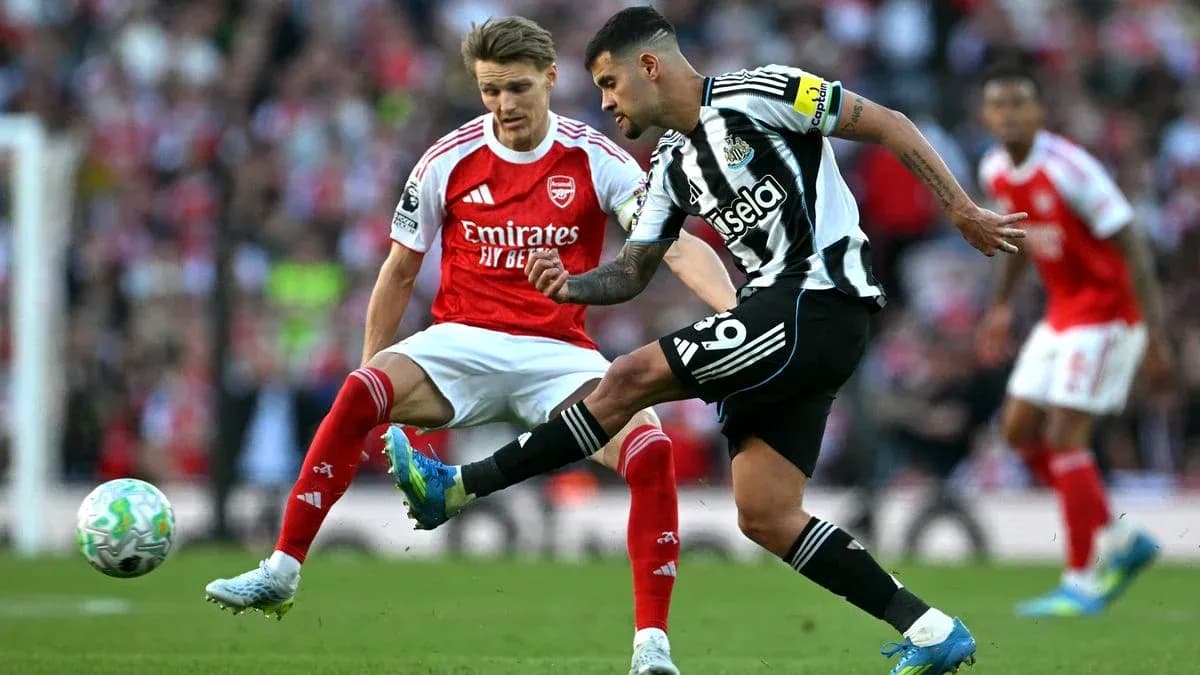 Newcastle player kicking ball past Arsenal defender