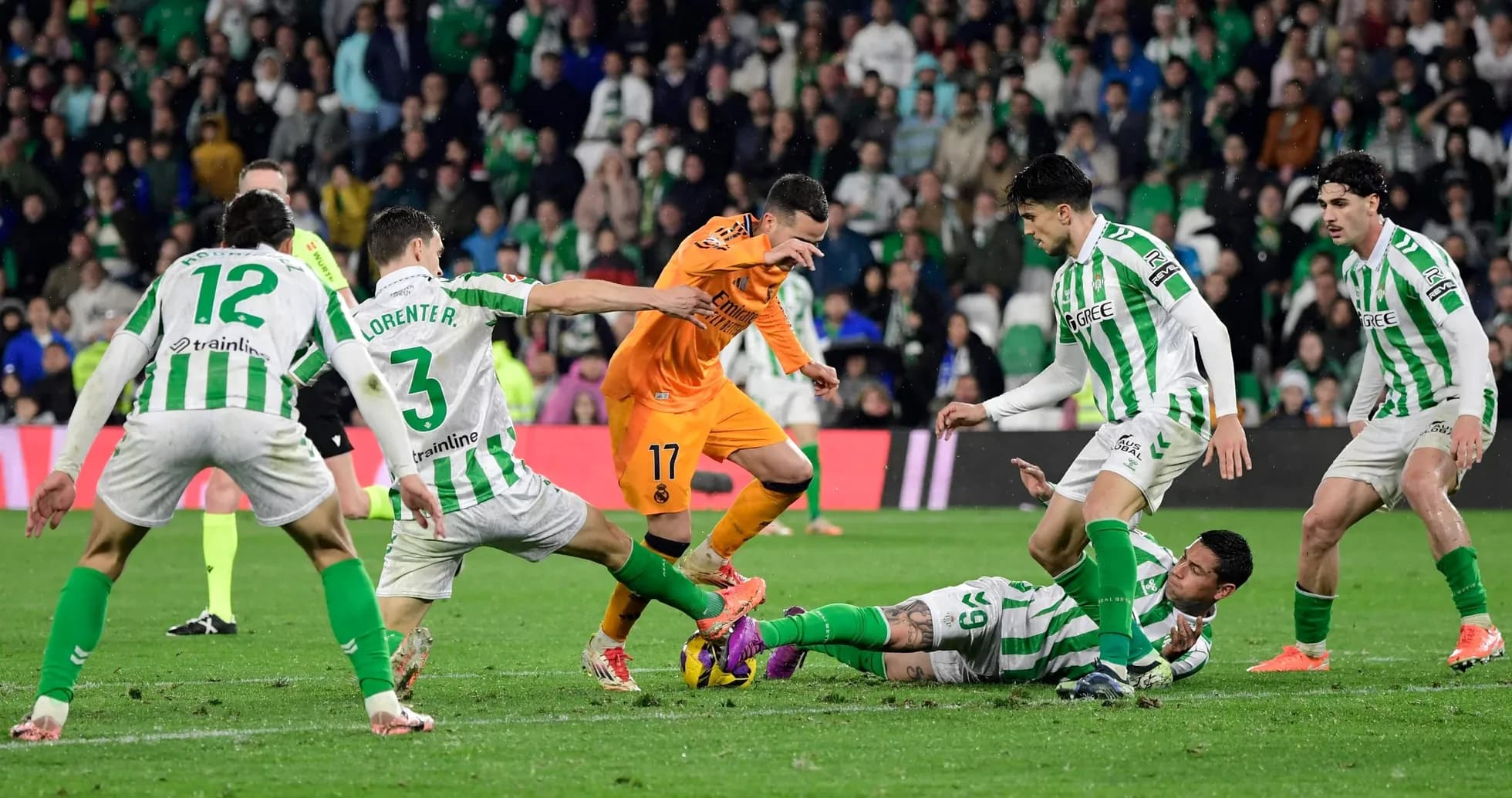 Real Betis players tackling Real Madrid forward