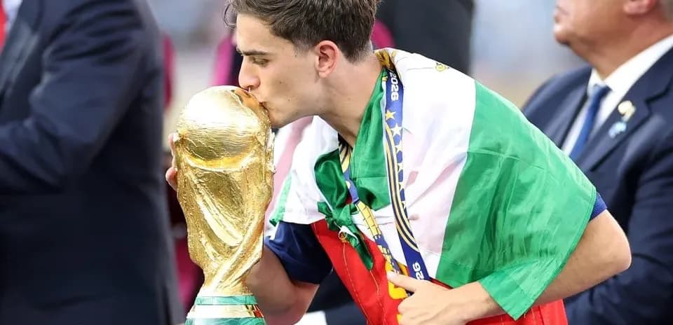 Player kissing FIFA World Cup trophy on podium