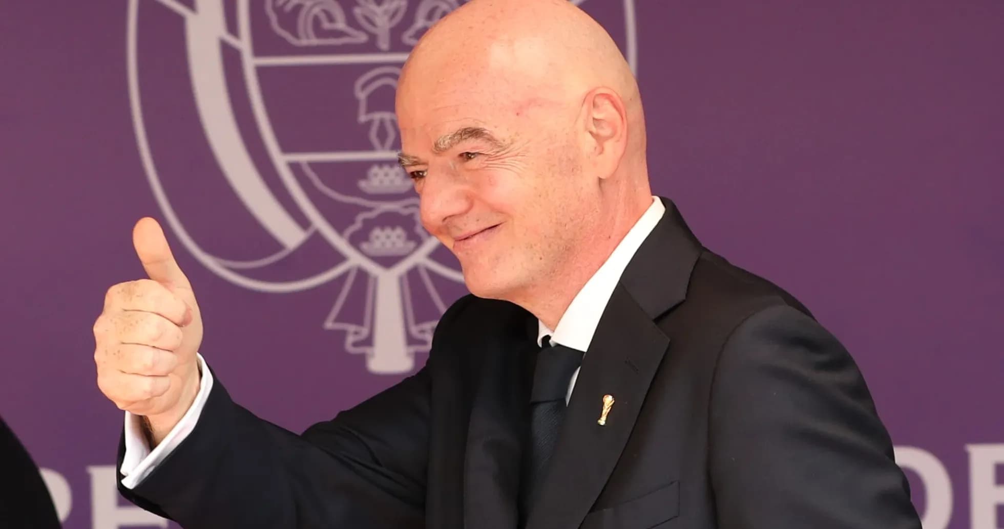 Man giving a thumbs up at event backdrop