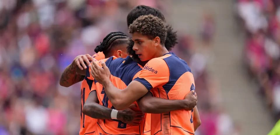 Players celebrating in orange jerseys during match