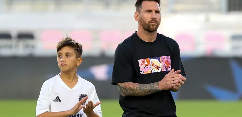 Lionel Messi and child clapping on field