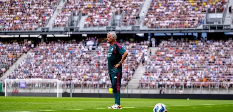 Coach observing the game with packed stadium behind
