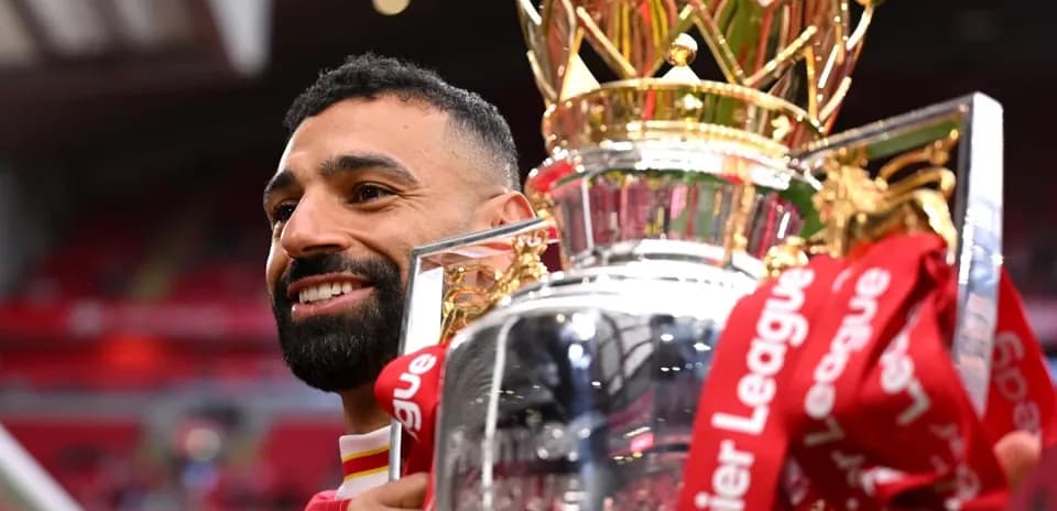 Player holding Premier League trophy at stadium