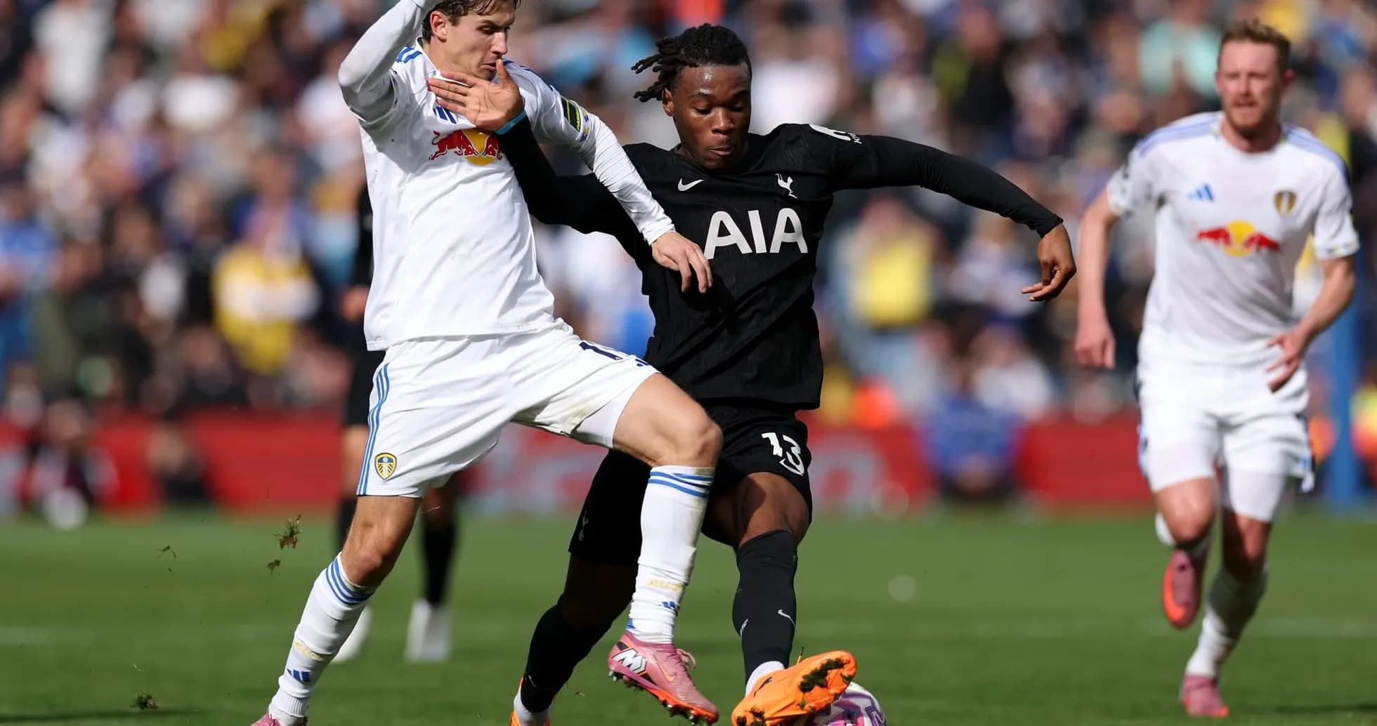 Leeds player challenges Tottenham player for the ball