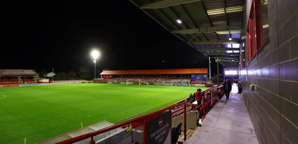 Empty football stadium at night with illuminated pitch