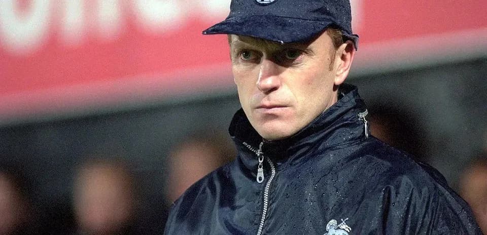 Coach in raincoat and cap on the sidelines